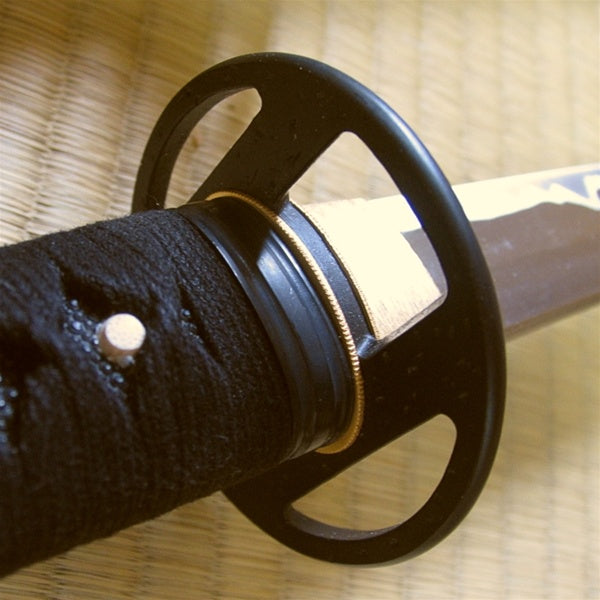 The simple black brass fuchi and tsuba seen from the ura side of the iaito.