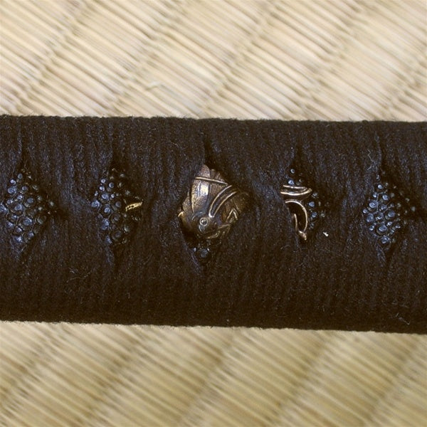 Cricket themed menuki beneath the hinerimaki black cotton wrapping