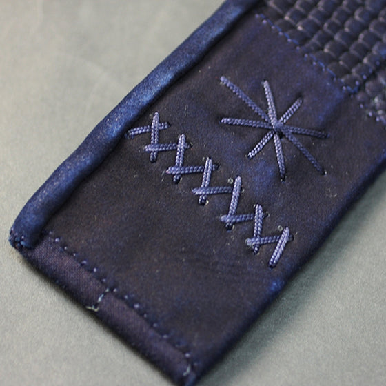 The leather reinforcements that attach the himo to the hara-obi of the tare.