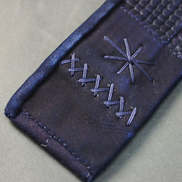 The leather reinforcements that attach the himo to the hara-obi of the tare.